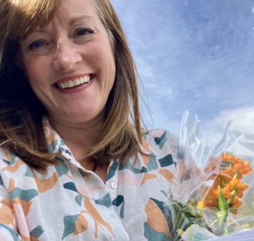Carla with orange flower bouquet delivery for doctors' offices with Hello Clinic scheduling updates.