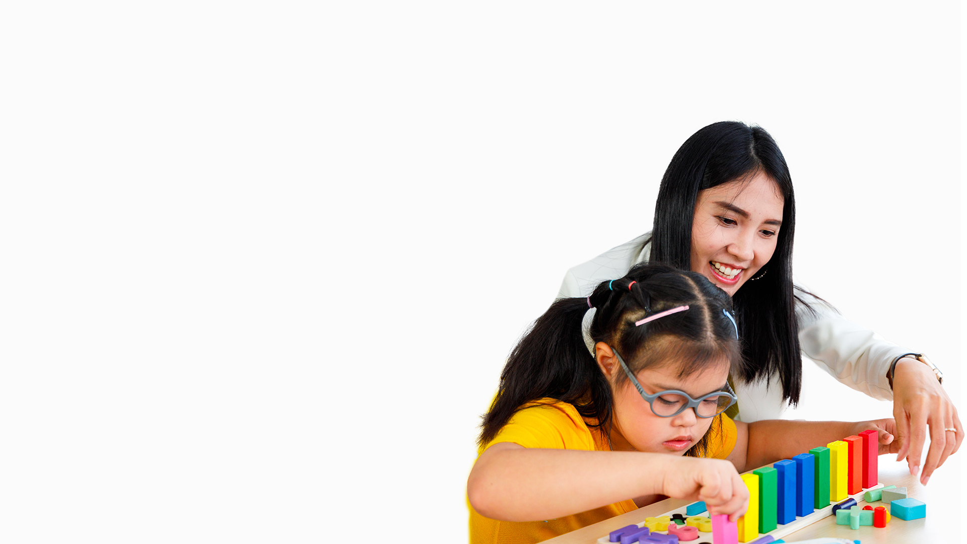 Asian girl with Downs syndrome play puzzle toy with her teacher in classroom-white-bg